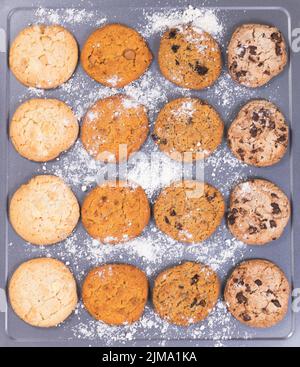 Verschiedene gebackene Plätzchen mit Mehl auf Backblech fertig zum Essen Stockfoto