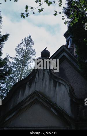 Eine vertikale Nahaufnahme einer alten mystischen Kirche aus einem niedrigen Winkel mit einem von hinten sichtbaren Baum Stockfoto
