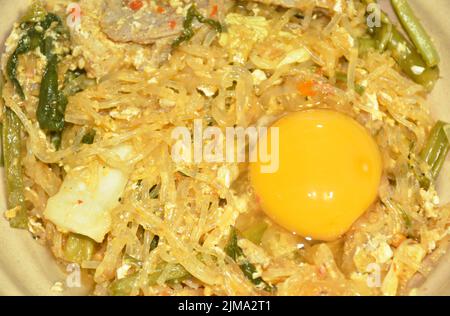 Gebratene Glasnudeln, Schweinefleisch und Hühnerfleisch mit Gemüsesukiyaki-Sauce auf Ei und auf einer Schüssel umrühren Stockfoto