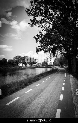 Eine Graustufenaufnahme einer Straße in der Nähe des Sees Stockfoto