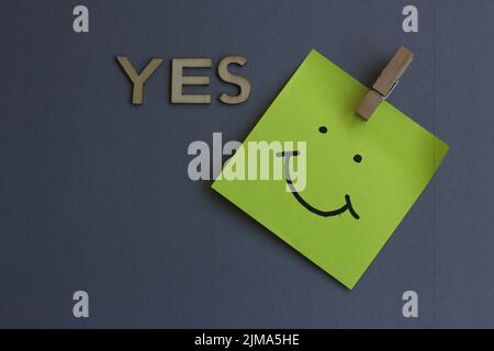 Smiley postit auf blaugrauem Grund mit dem Wort Ja Stockfoto