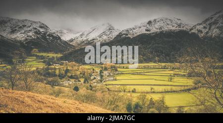 Das kleine Dorf Rosthwaite im Borrowdale Valley, umgeben von schneebedeckten Bergen. Stockfoto