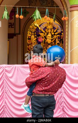 Howrah, Indien -26.. Oktober 2020 : Vater mit Helm auf, zeigt Göttin Durga seinem Kind, Durga im Alter dekoriert Haus. Durga Puja. Stockfoto