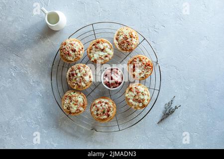 Miniportionen von Flammekueche oder Flammkuchen, französische und deutsche Spezialität, auf dem runden Kühlgitter aus Metall, Draufsicht Stockfoto