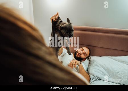Mann hält seinen Hund von der Haut, Französisch Bulldog sieht so erbärig, nachdem er beißen Menschen zu Hause Stockfoto