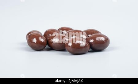 Schokoladennüsse auf grauem Hintergrund, schokoladenbeschichtete Erdnüsse. Stockfoto