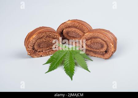 Süße Biskuitrolle mit thc und grünem Cannabisblatt. Stockfoto