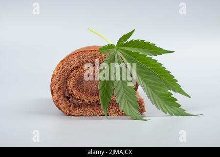 Süße Biskuitrolle mit thc und grünem Cannabisblatt. Stockfoto