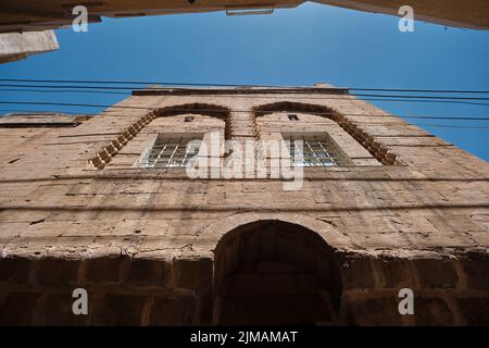 Traditionelle Hausfassade, traditionelle enge Straßen im alten Mardin. Blick in den niedrigen Winkel und Blick auf den schmalen Himmel von den Straßen von Mardin. Stockfoto