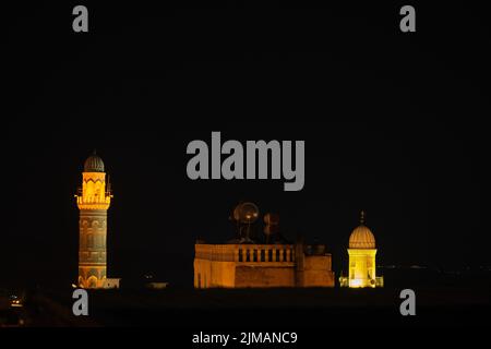 Nacht in Mardin City, Ansicht der alten Moschee Minarette, beleuchtete Gebäude im alten Mardin. Stockfoto