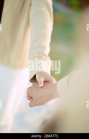 Eine vertikale Nahaufnahme der Hand einer Frau, die die Faust des Mannes sanft hält. Stockfoto