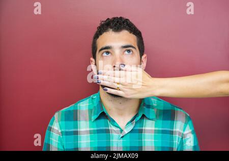 Tolles Konzept der weiblichen Zensur, Mann mit dem Mund von Frau Hand abgedeckt. Stockfoto