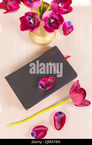 Heilige Bibel mit Blumen auf hölzernen Tisch Stockfoto