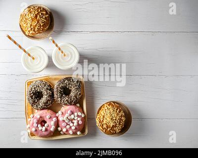 Frische Donuts zum Mitnehmen in einer recycelbaren Schachtel mit zwei Pappbecher mit Kaffee Stockfoto