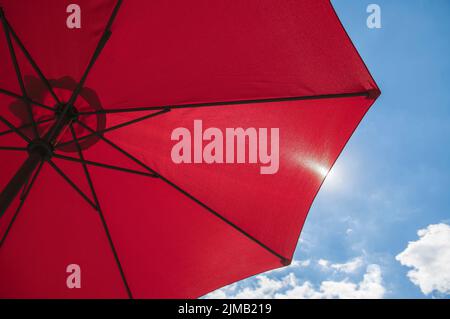 Roter Strandschirm vor blauem Himmel Stockfoto