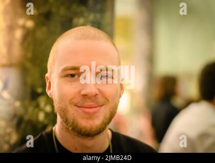 Eine flache Fokusaufnahme eines kaukasischen Mannes, der charmant lächelt Stockfoto