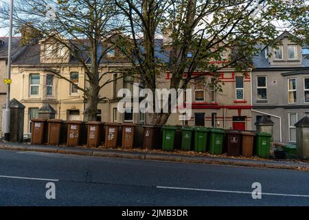 Reihe von grünen und braunen Mülltonnen auf einer Alexandra Road mit Erkerfensterhäusern im Hintergrund. Stockfoto