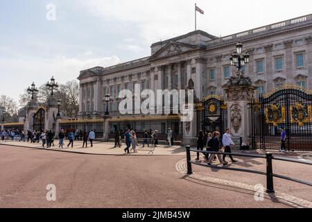 Eine Winkelaufnahme des Buckingham Palace, Blick auf das Eingangstor mit Touristen und der Unionsflagge am vollen Mast Stockfoto