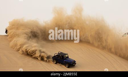 Eine Luftaufnahme eines Offroad-Jeeps, der auf einem Wüstensand aufzeigt Stockfoto