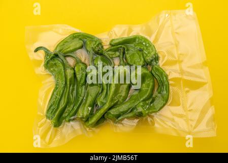 Friggitelli, toskanische oder griechische milde Paprika, auch Pepperoncini genannt, im Vakuum verpackt, versiegelt für Sous-Vide-Kochen isoliert auf gelbem Hintergrund oben Stockfoto