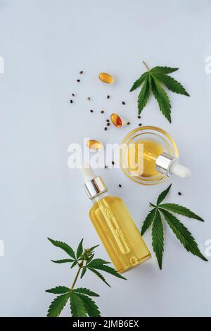 CBD-Öl in der Flasche mit Pipette, Kapseln, Marihuanablättern auf weißem Hintergrund Stockfoto