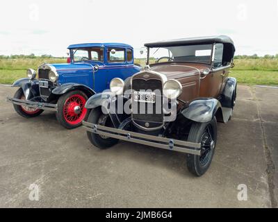 Altes braunes Ford Modell A Phaeton Fordor viertürig und blaues Coupé Tudor zweitürig um 1930. Vorderansicht. CADEAA MNA 2022 Oldtimer-Show. Stockfoto