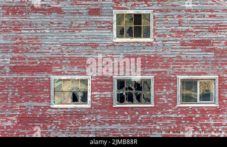 Nahaufnahme einer roten Holzmauer in einer verlassenen Bergbaustadt mit abblätternder Farbe und kaputten Fenstern in Ivittuut, Grönland, am 21. Juli 2022 Stockfoto