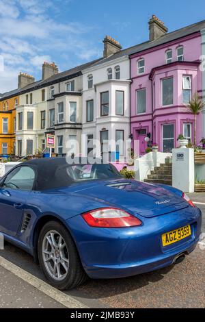 Eine vertikale Aufnahme eines blauen Porsche Boxsters, der vor den Gebäuden von Bangor, Vereinigtes Königreich, geparkt ist Stockfoto