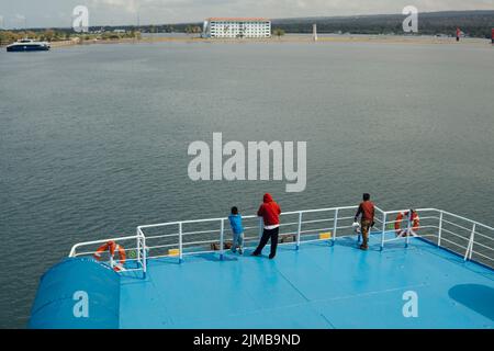 Kayangan, Nord-Lombok, Indonesien - 9. Juli 2022: Vater und Sohn, die am Hafen von der Seite des Fährschiffs, das andocken wird, die Hauptrolle spielen Stockfoto