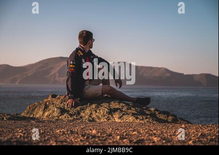 Ein Mann mit Brille sitzt am Meeresufer und blickt in San Francisco, USA, zum Horizont Stockfoto
