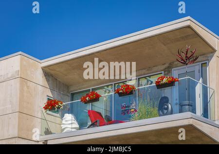 Glasbalkone eines modernen Apartmentgebäudes in einem Wohngebiet. Balkon der modernen Wohnung mit Pflanzen an sonnigen Tagen. Niemand, Straßenfoto Stockfoto