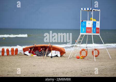 Rettungsschwimmer verstecken sich während eines Sturms am Strand im Rettungsboot Stockfoto