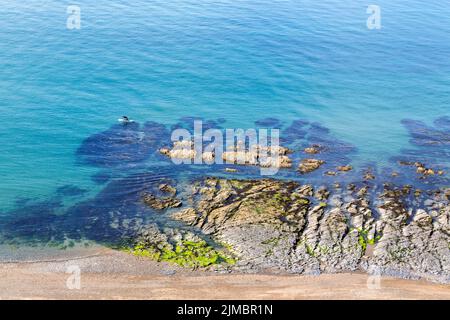 Ein Mann kniet auf einem Paddelbrett und paddelt entlang einer malerischen Küste. Gesundheit, Fitness, Urlaub, Urlaub, Zeit allein, Ihr Zeitkonzept. Stockfoto