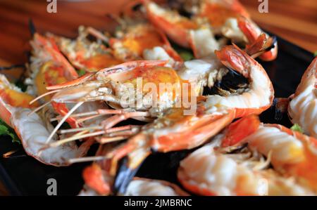 Nahaufnahme von thailändischem Essen, frische Riesengarnelen, gegrillt auf traditionellem Holzkohlegrill, serviert mit einer würzigen Dip-Sauce im thailändischen Stil. Stockfoto