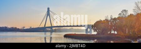 Nebliger Herbstaufgang auf dem Fluss Dnjepr mit Blick auf die Pivnichnyj (nördliche) Brücke im Hintergrund, Kiew, Ukraine Stockfoto