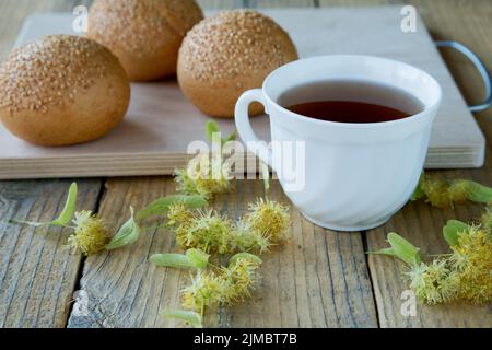 Tasse Tee mit Lindenblüten auf einem rustikalen Tisch Stockfoto