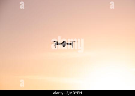 Die Drohne ist bei Sonnenuntergang im Flug. Videoaufnahmen von oben. Ein Artikel über die Wahl eines Quadrocopters. Vor- und Nachteile der Drohne. Sonnenuntergang Stockfoto