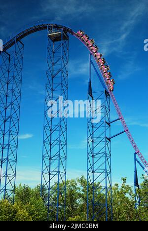 Abenteuerlustige begeben sich in Six Flags New England in den Abstieg von Superman the Ride, der oft als einer der besten Roller Coaster der Welt gilt, Stockfoto