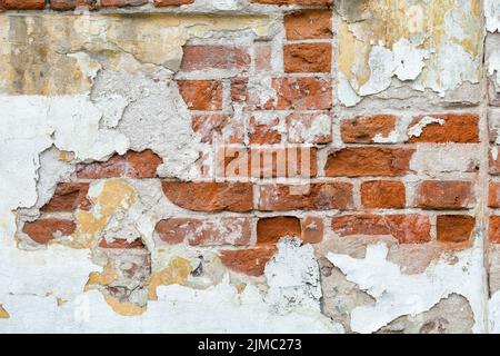 Die Textur der alten Ziegelmauer mit den Spuren des grauen Putzes Stockfoto