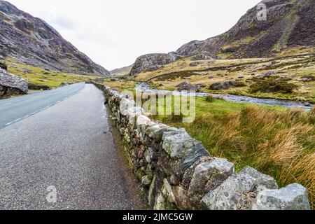 Magnificent Mountain Pass. Die Straße A4086 und der Llanberis Pass. Snowdonia, Gwynedd, Wales, Vereinigtes Königreich, Landschaft, Steinmauer im Vordergrund Stockfoto