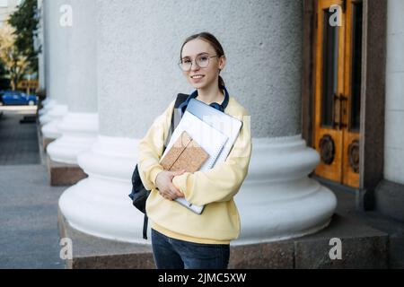 Stipendien für Studenten. Happy College Student Mädchen mit Laptop und Bücher in der Nähe der Hochschule Stockfoto