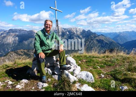 Reifen Wanderer sitzen auf Peak und lächelnd und Suchen auf der Kamera. Stockfoto