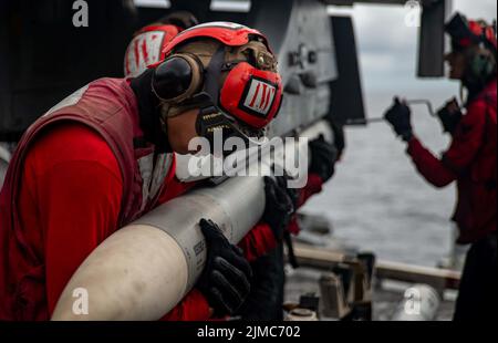 Pazifik, Usa. 04. August 2022. Die Matrosen der US-Marine laden auf eine F/A-18E Super Hornet, die an den „Dambustern“ der Strike Fighter Squadron 195 befestigt ist, auf dem Flugdeck des Flugzeugträgers USS Ronald Reagan der Nimitz-Klasse, der am 4. August 2022 in der philippinischen See unterwegs ist. Kredit: MC3 Gray Gibson/Planetpix/Alamy Live Nachrichten Gutschrift: Planetpix/Alamy Live Nachrichten Stockfoto