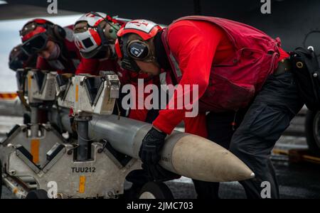 Pazifik, Usa. 04. August 2022. Die Matrosen der US-Marine laden auf eine F/A-18E Super Hornet, die an den „Dambustern“ der Strike Fighter Squadron 195 befestigt ist, auf dem Flugdeck des Flugzeugträgers USS Ronald Reagan der Nimitz-Klasse, der am 4. August 2022 in der philippinischen See unterwegs ist. Kredit: MC3 Gray Gibson/Planetpix/Alamy Live Nachrichten Gutschrift: Planetpix/Alamy Live Nachrichten Stockfoto