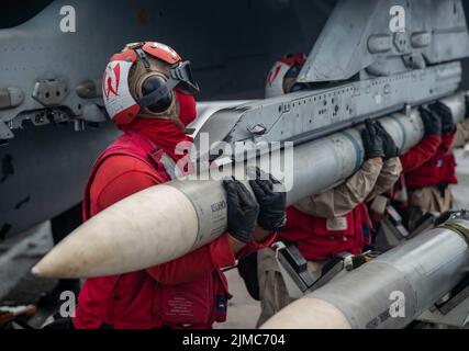 Pazifik, Usa. 04. August 2022. Die Matrosen der US-Marine laden auf eine F/A-18E Super Hornet, die an den „Dambustern“ der Strike Fighter Squadron 195 befestigt ist, auf dem Flugdeck des Flugzeugträgers USS Ronald Reagan der Nimitz-Klasse, der am 4. August 2022 in der philippinischen See unterwegs ist. Kredit: MC3 Gray Gibson/Planetpix/Alamy Live Nachrichten Gutschrift: Planetpix/Alamy Live Nachrichten Stockfoto