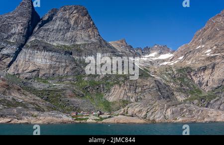 Am 22. Juli 2022 wurde Aappilattoq von schneebedeckten Bergen im Prince Christian Sound, Südgrönland, in den Schatten gestellt Stockfoto