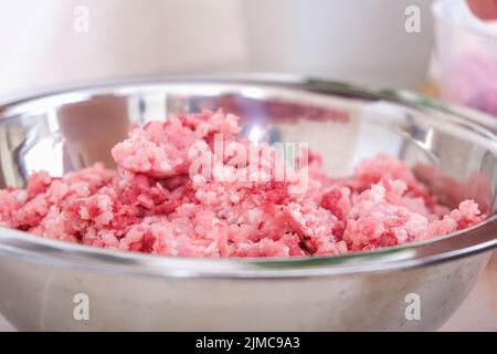 Ein Mann mischt Hackfleisch in einer Schüssel mit seinen Händen. Zubereitung von Hackfleisch und Schweinefleisch für Koteletts, Fleischbällchen, Koteletts. Stockfoto