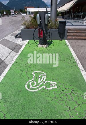 Elektrofahrzeug (EV) Ladestation Parkplatz mit Symbol Text über das Altern grün lackierten Pflaster. Stockfoto