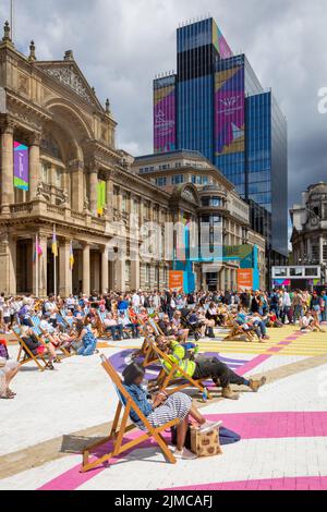 Zuschauermenge, die die Sommersonne am Victoria Square Birmingham genießt und dabei eine Großleinwand der Commonwealth Games 2022 sieht Stockfoto