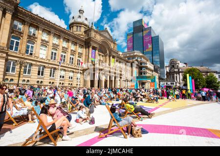 Zuschauermenge, die die Sommersonne am Victoria Square Birmingham genießt und dabei eine Großleinwand der Commonwealth Games 2022 sieht Stockfoto